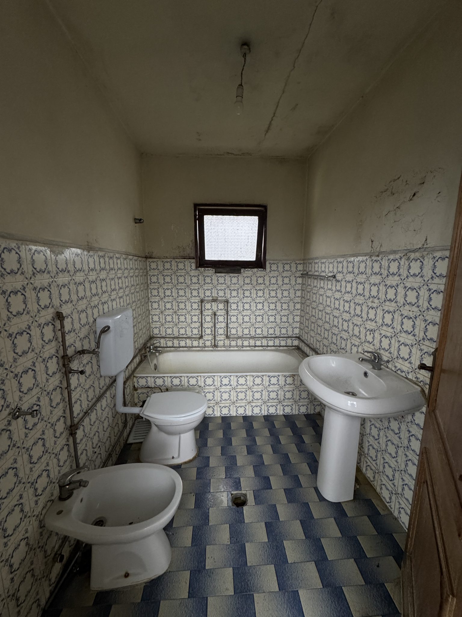 casa de banho antiga em Braga antes de remodelação, com azulejos e desgaste visível