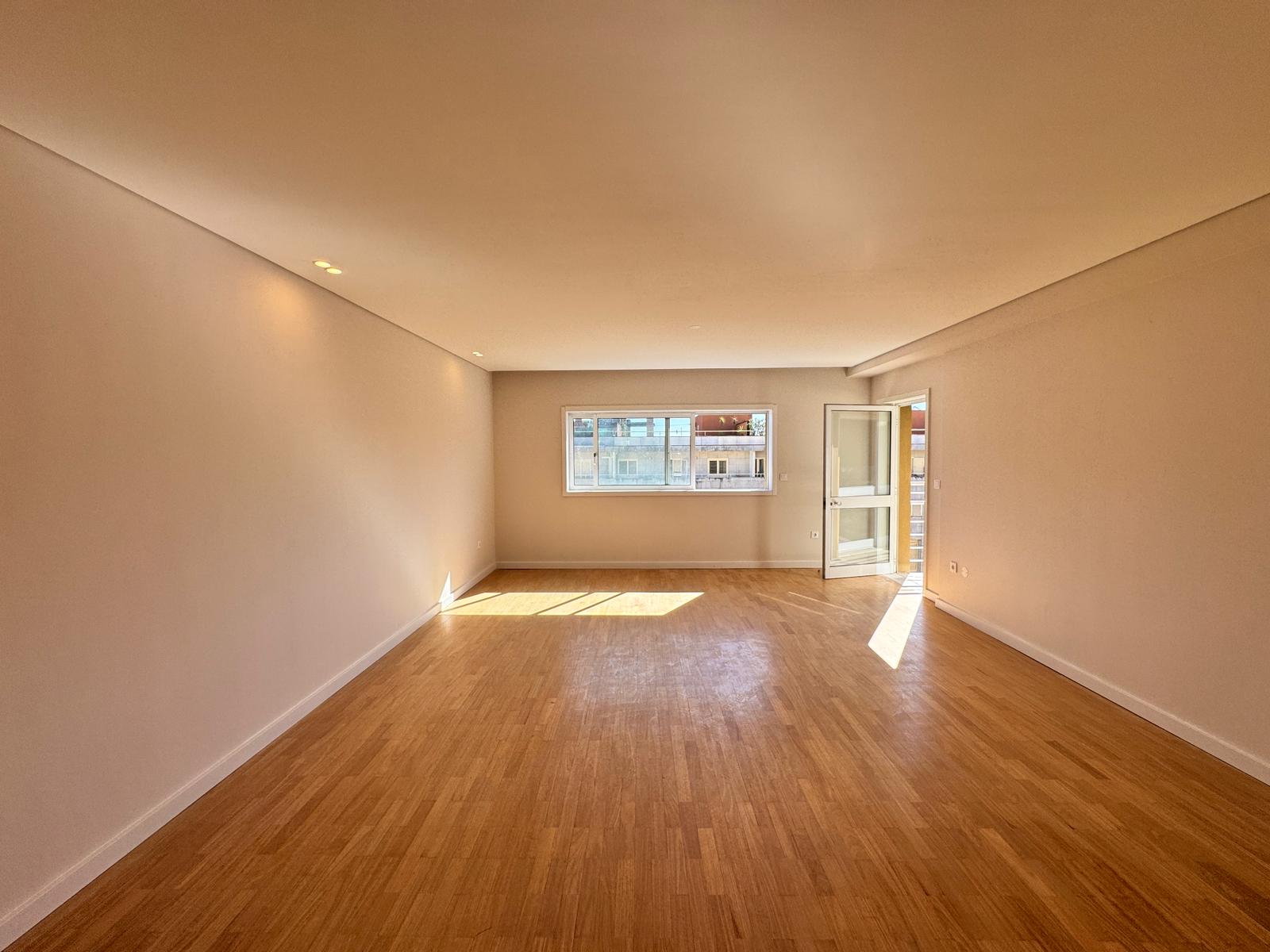 sala ampla de apartamento reabilitado em Braga com piso em madeira e luz natural